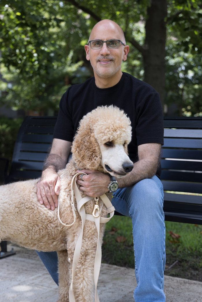 The owner of Clayton Dog Sitters sitting on a park bench with a standard poodle in Clayton, MO
